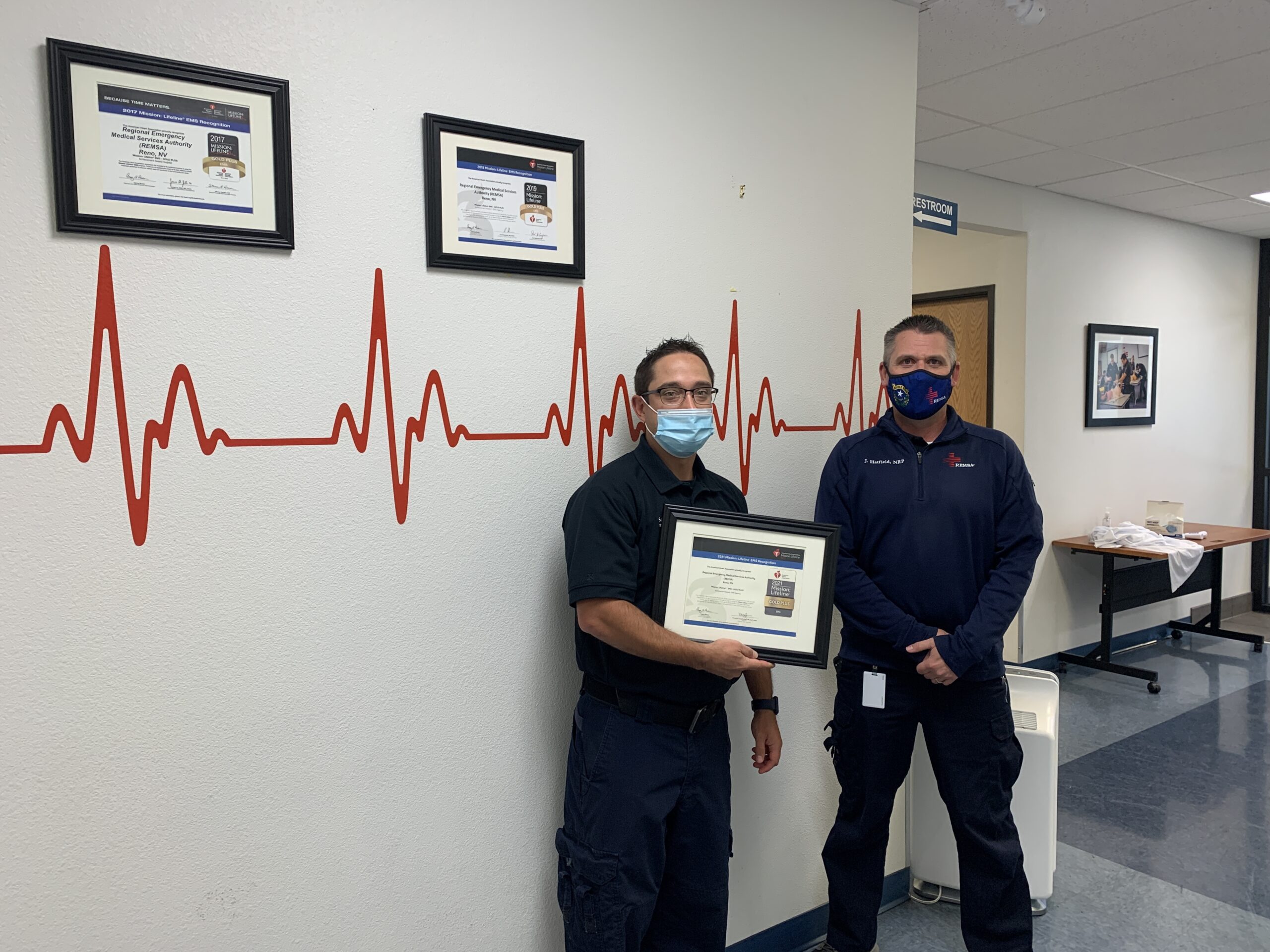 Two employees hold an award